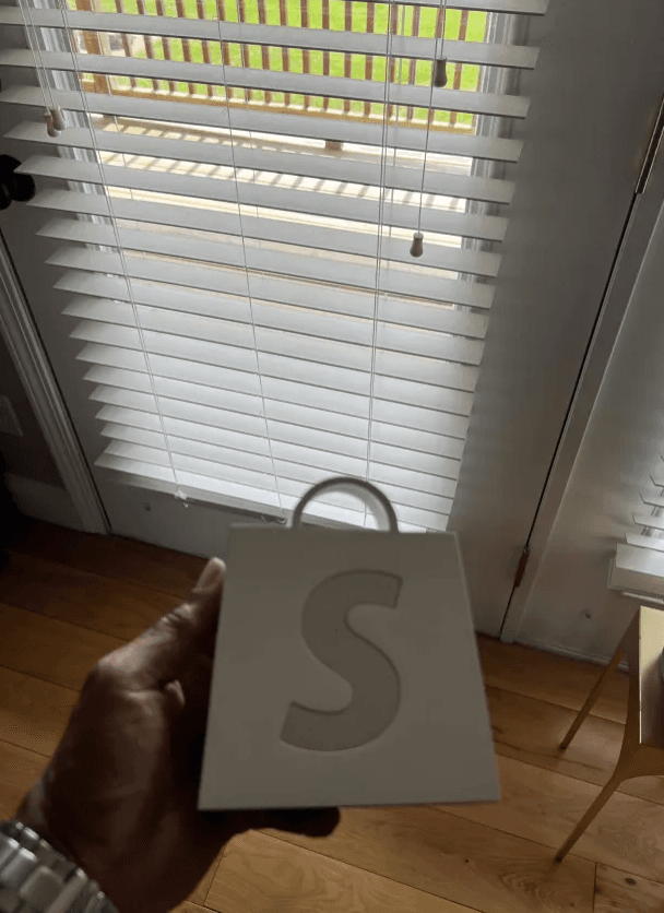Hand holding a Shopify branded shipping bag from a fulfilled student store order